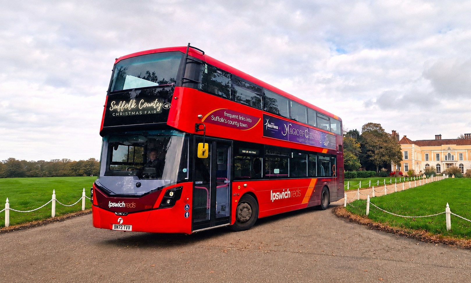 A red shuttle bus arriving at Hintlesham Hall for Suffolk County Christmas Fair
