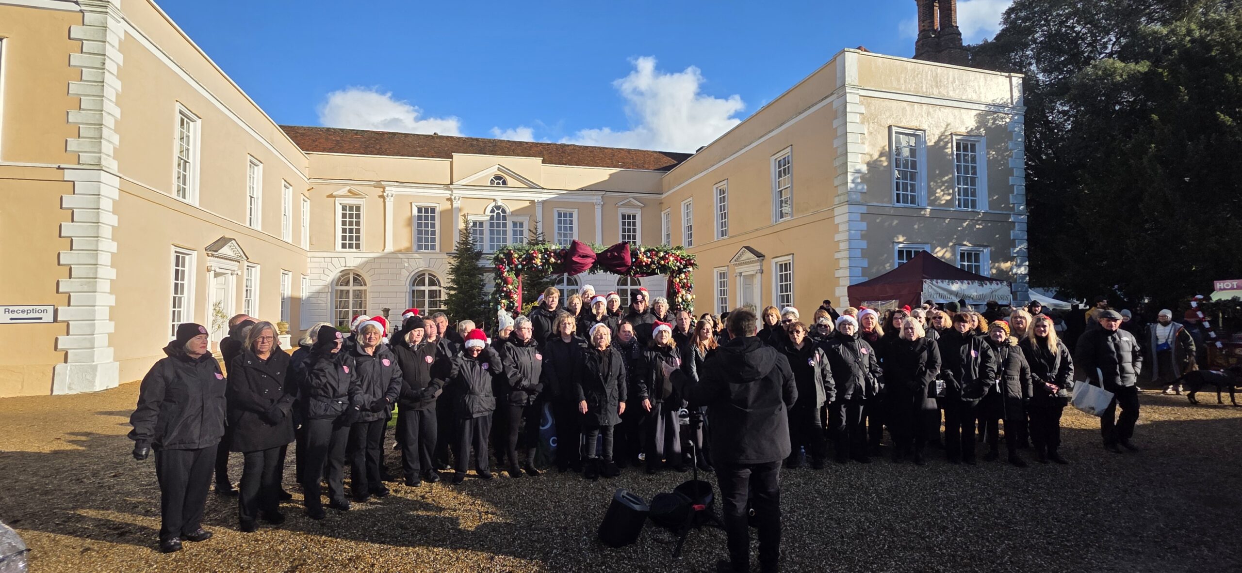 A choir performing outside Hintlesham Hall at Suffolk County Christmas Fair