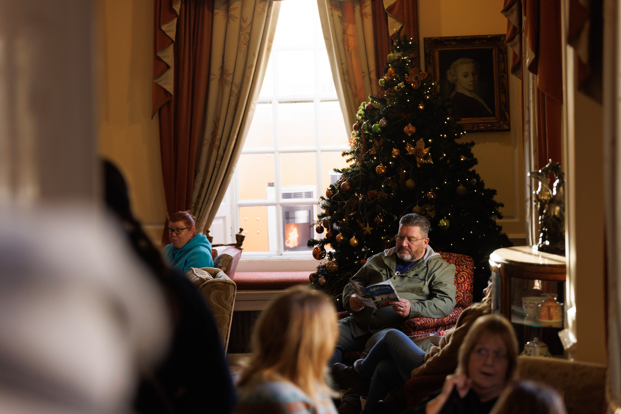 A visitor relaxing beside the Christmas tree in Hintlesham Hall’s lounge