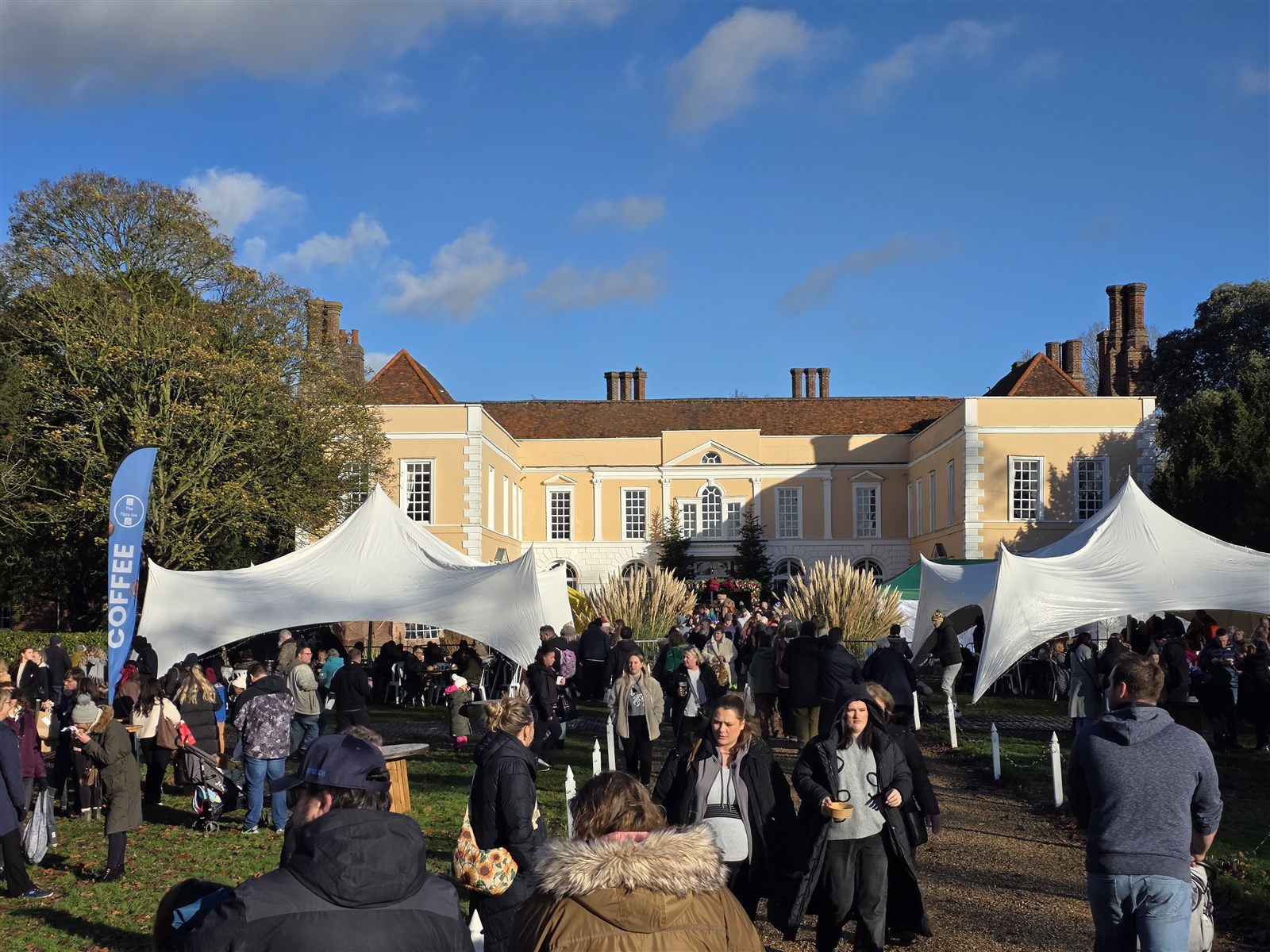 Visitors and white marquees outside Hintlesham Hall in the sunshine